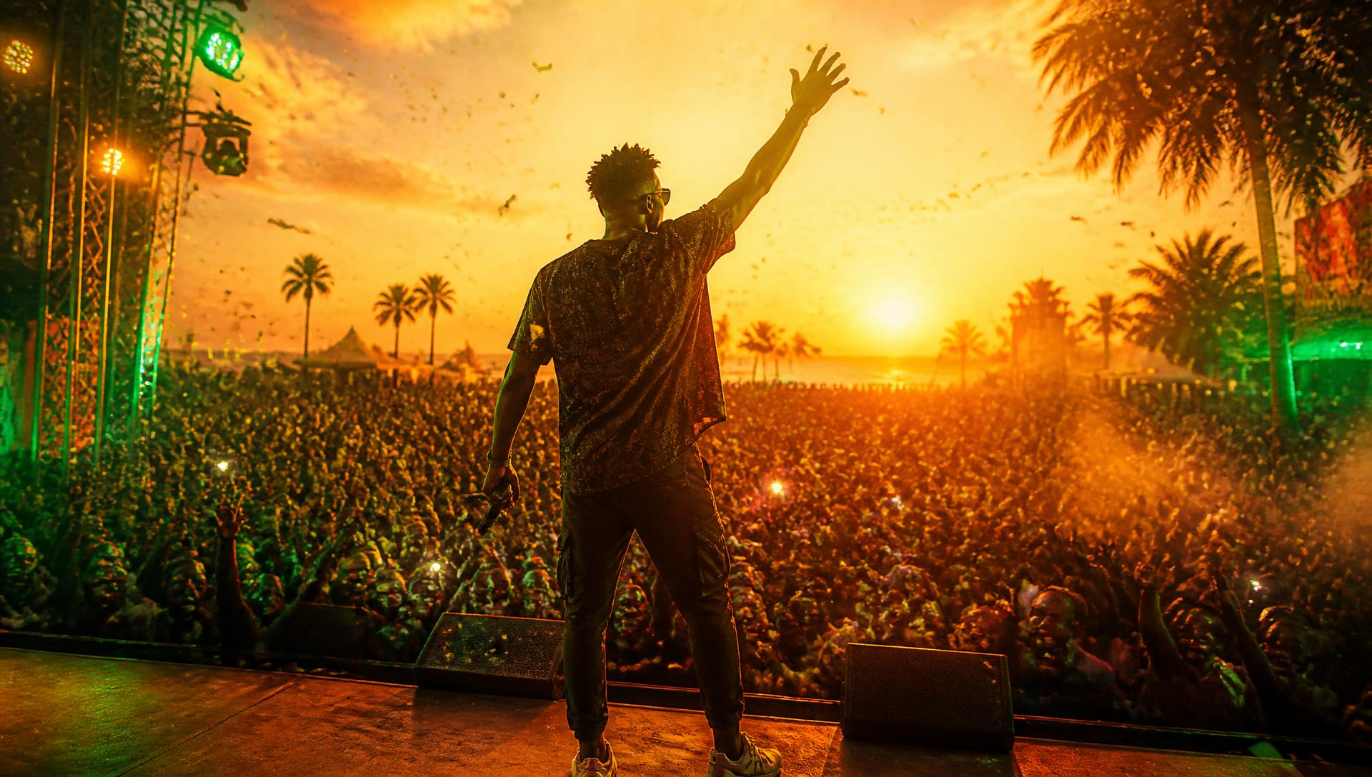 Afrobeats artist performing to a sunset festival crowd